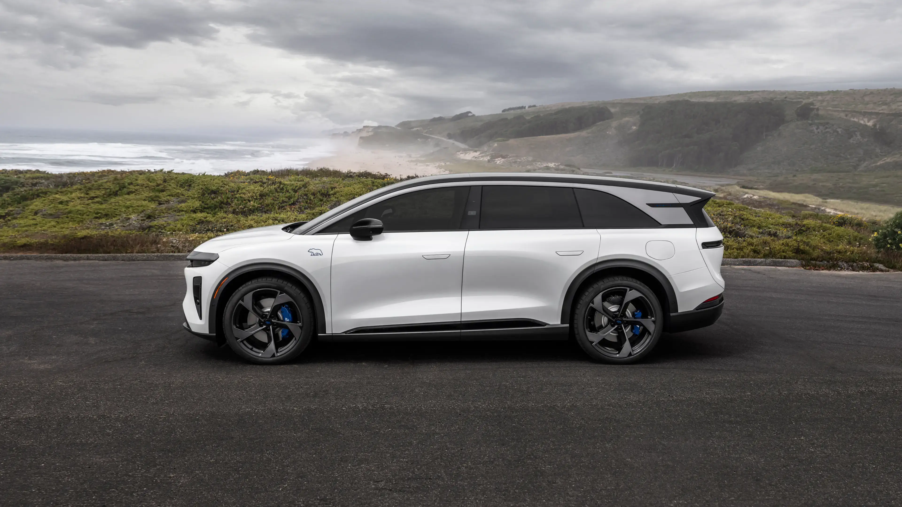 White 2027 Lucid Gravity GT-S electric SUV parked above a coastal road