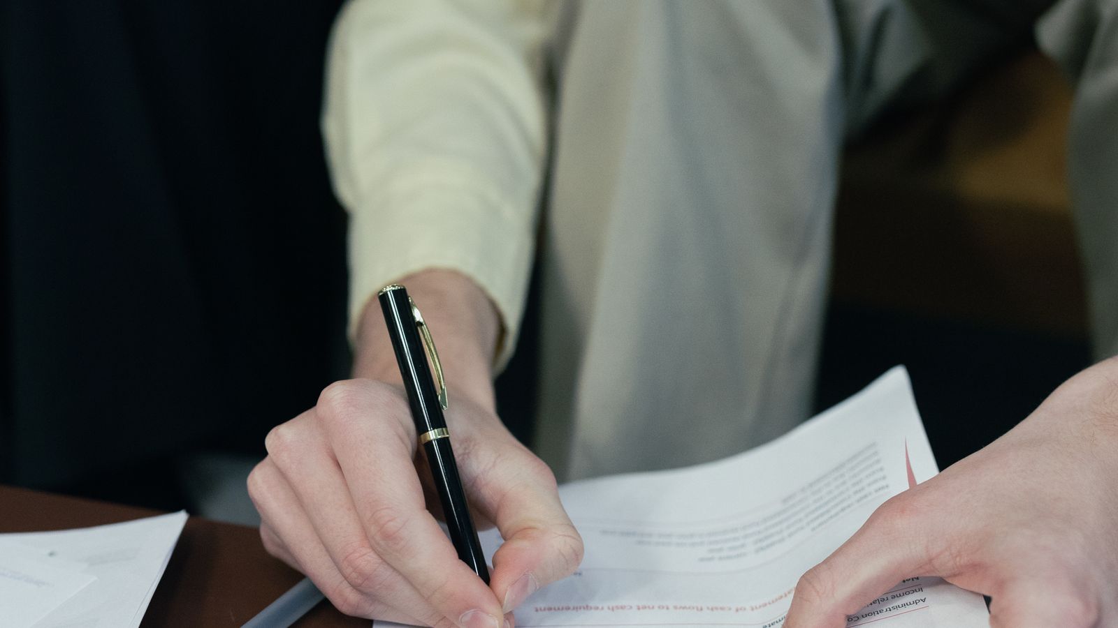 Close-up of a person reviewing and signing financial paperwork